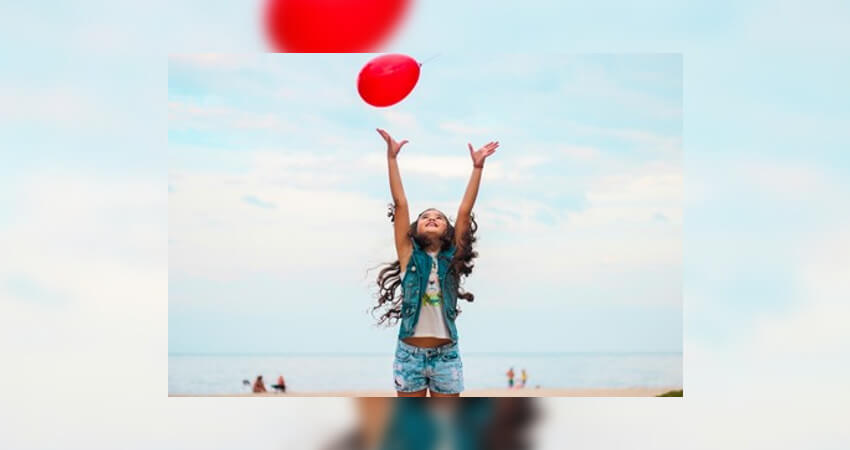 η καλή ψυχολογία του παιδιού που παίζει με ένα κόκκινο μπαλόνι