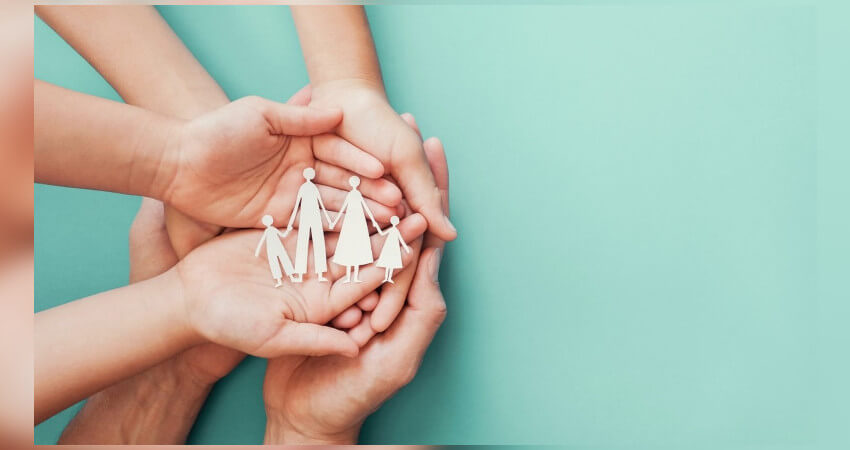 ενωμένα χέρια με ένα χάρτινο σχέδιο που απεικονίζει μια τετραμελής οικογένεια