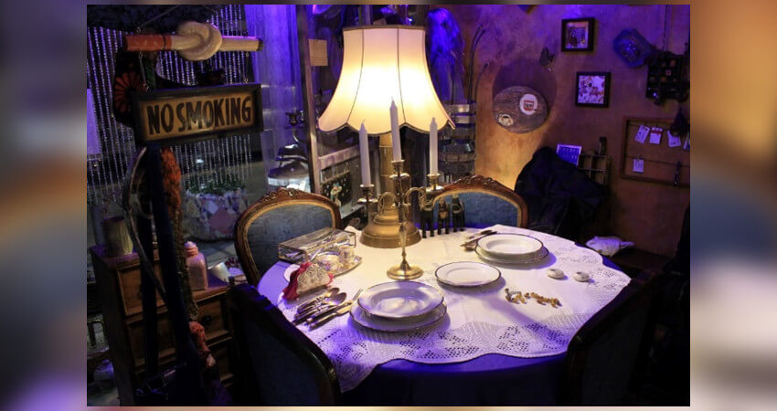 Τραπέζι στρωμένο με σερβίτσια, αναμμένο φωτιστικό, φόντο διακοσμητικά