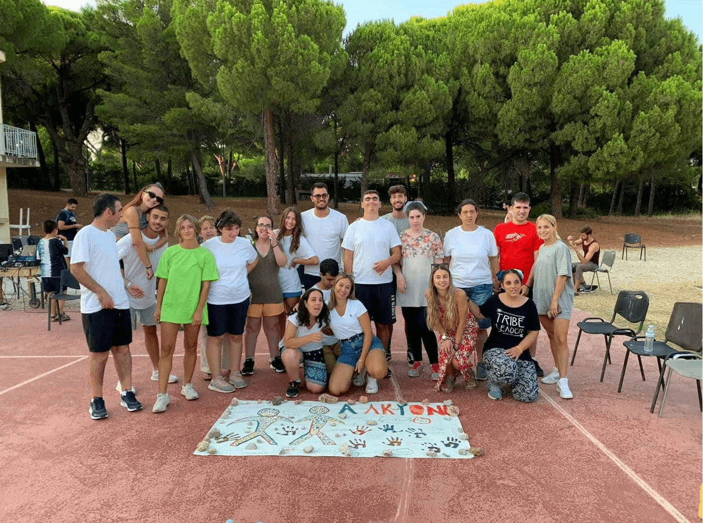 Ομάδα νέων τυπικής μάθησης και ειδικής ποζάρουν μπροστά από μια αφίσα του συλλόγου Αλκυόνης